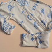 Baby onesie with blue geometric patterns on a beige background