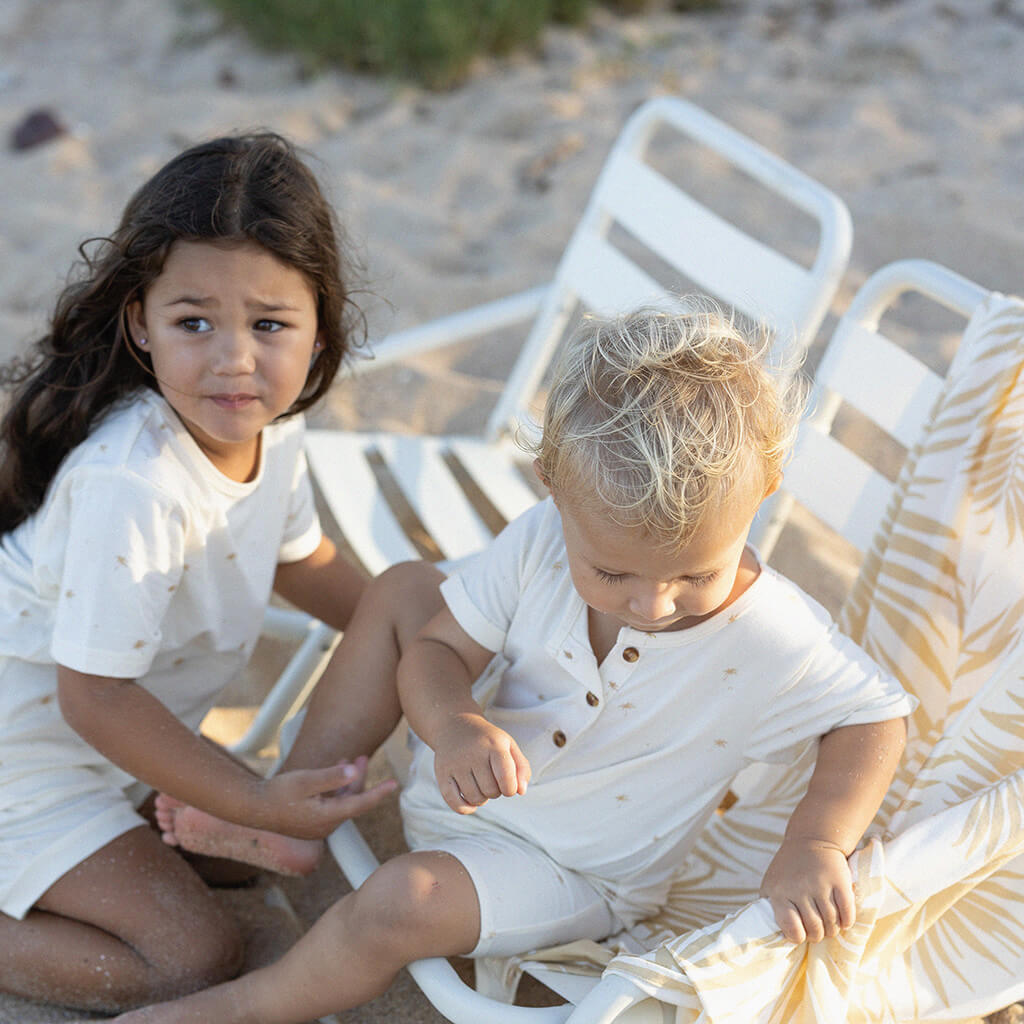 kids wearing wearing cream jumpsuit and tee with palm tree print