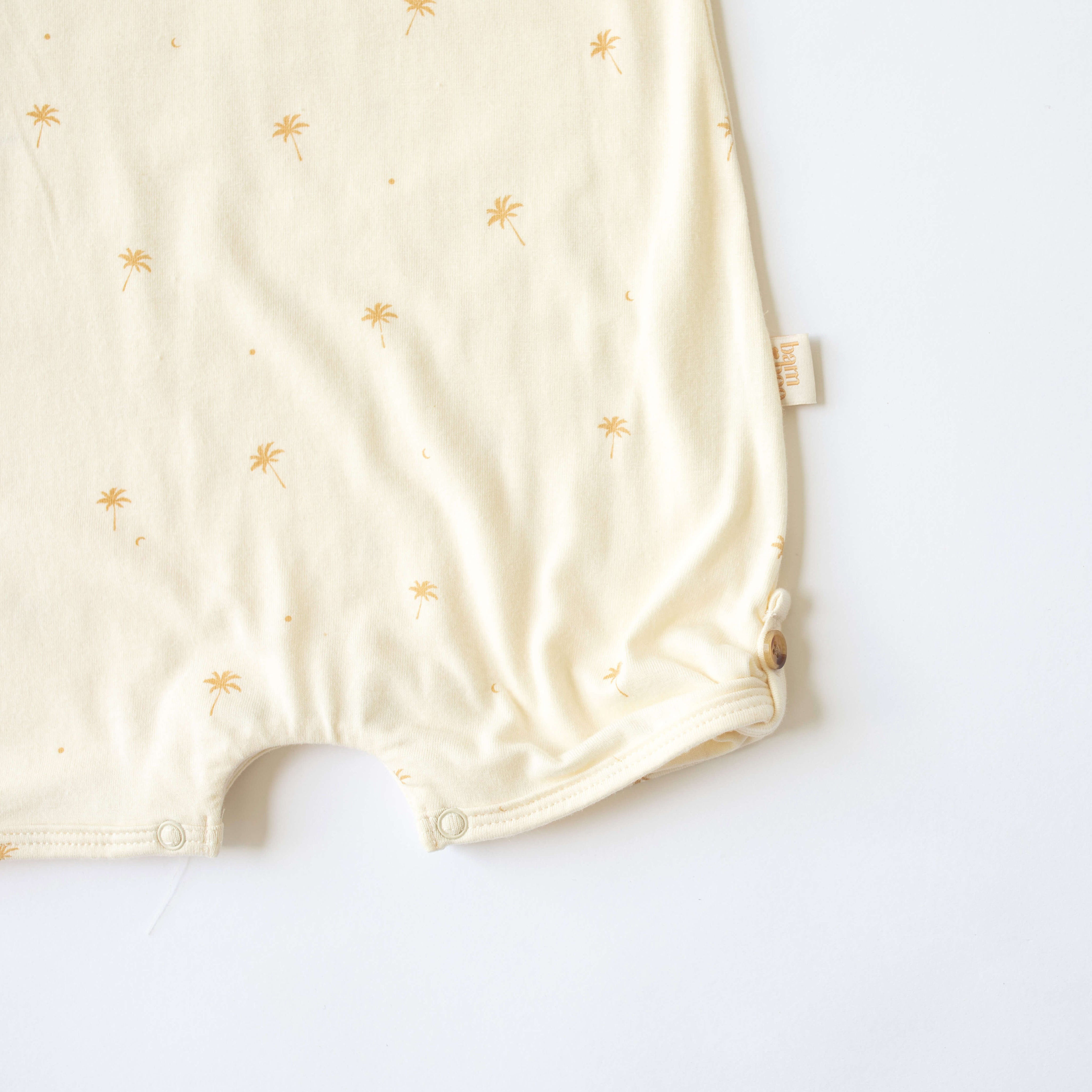 close up of palm tree printed onesie with button up leg feature