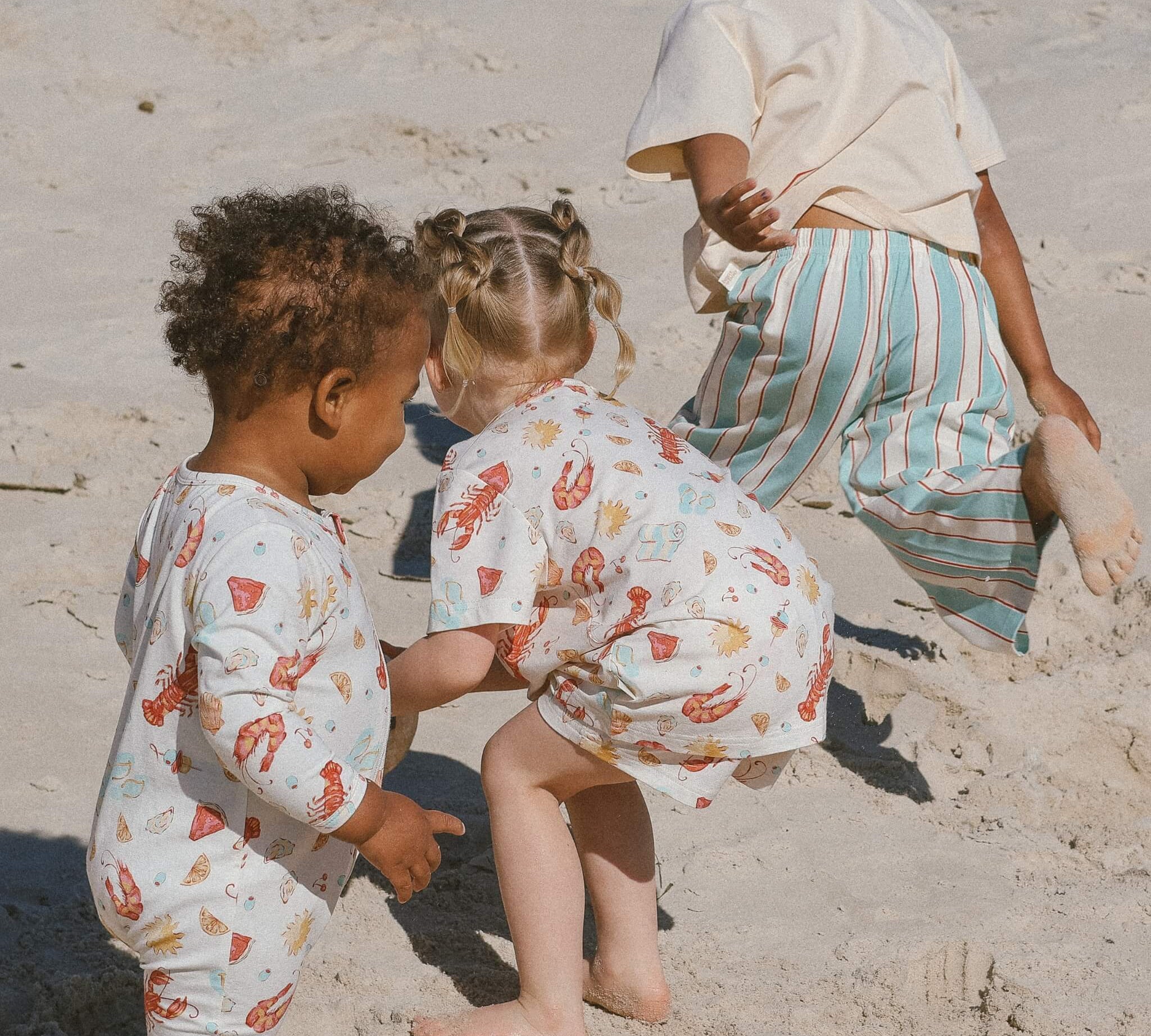 Children playing in the sand wearing the Aussie summer print range by Bam Loves Boo, thoughtful Christmas gifts that last