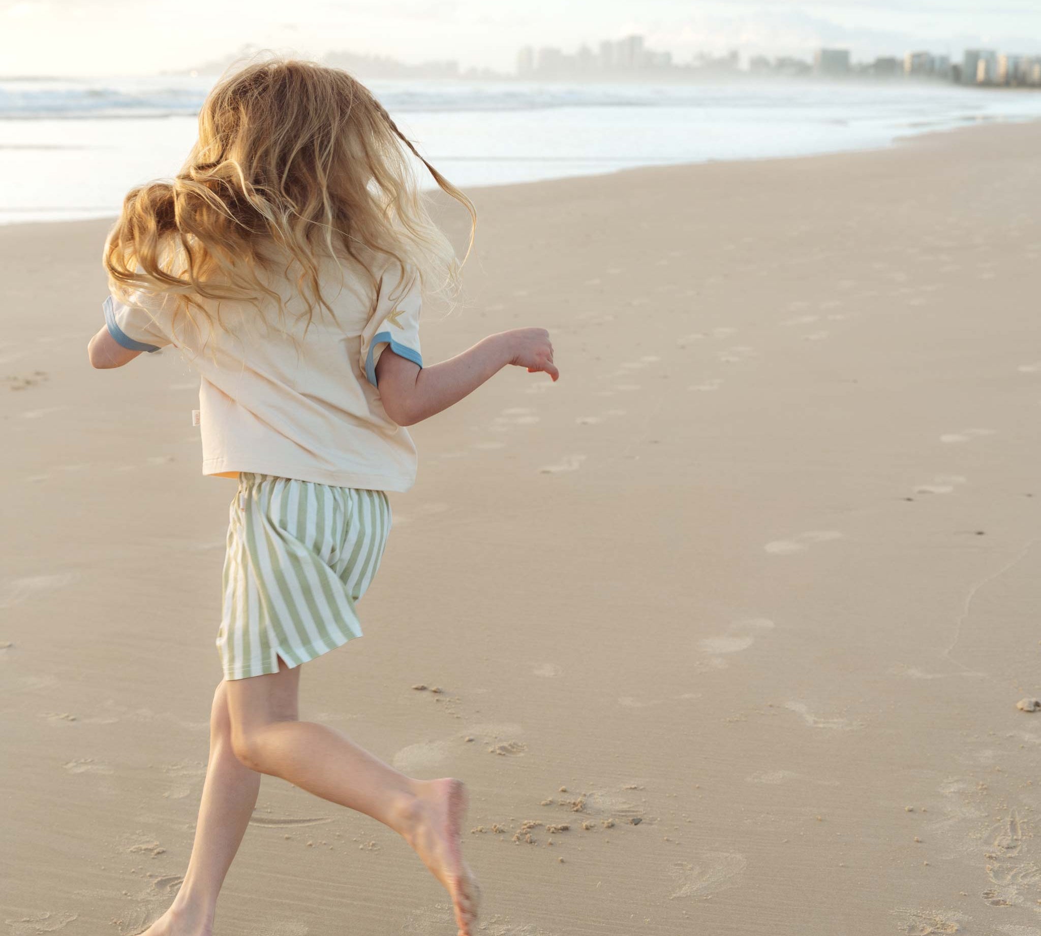 Girl running across beach in early morning sun wearing Bam Loves Boo spring collection