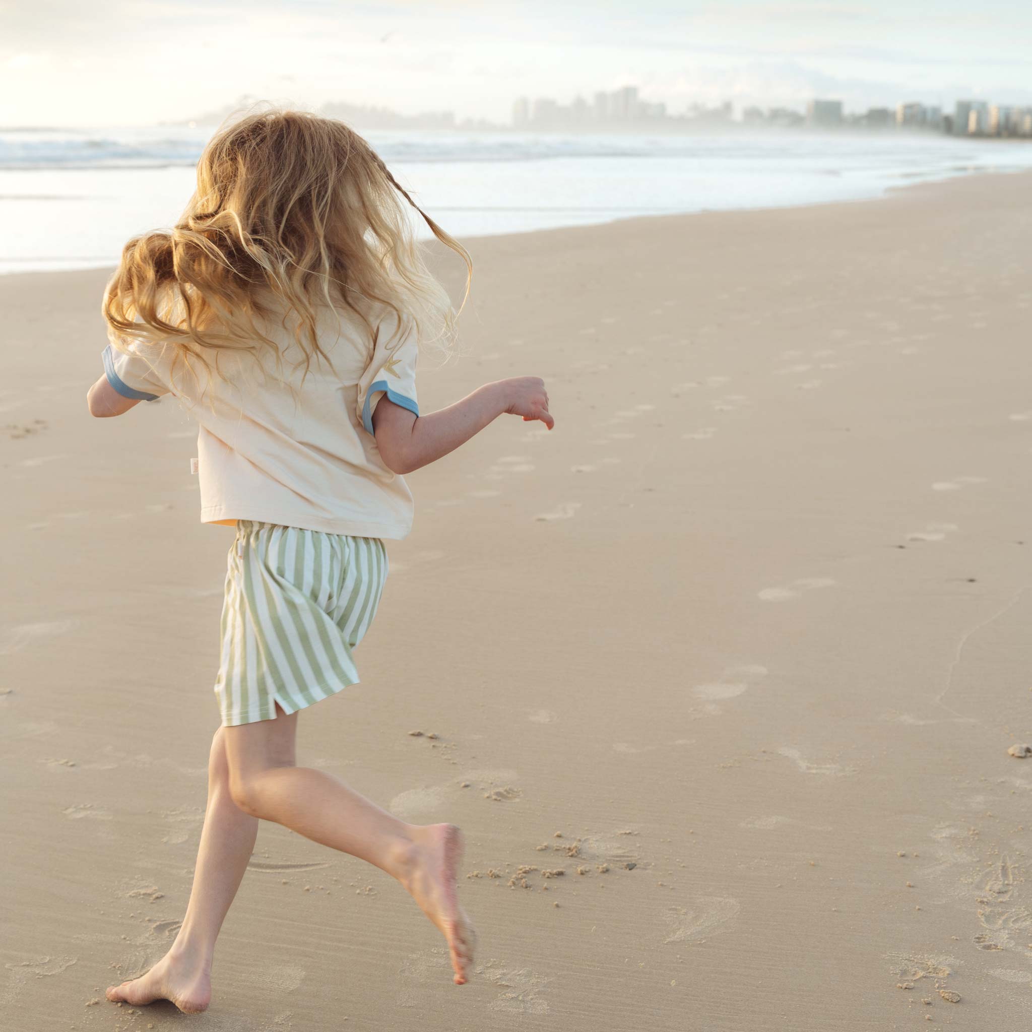 Girl running across beach in early morning sun wearing Bam Loves Boo spring collection