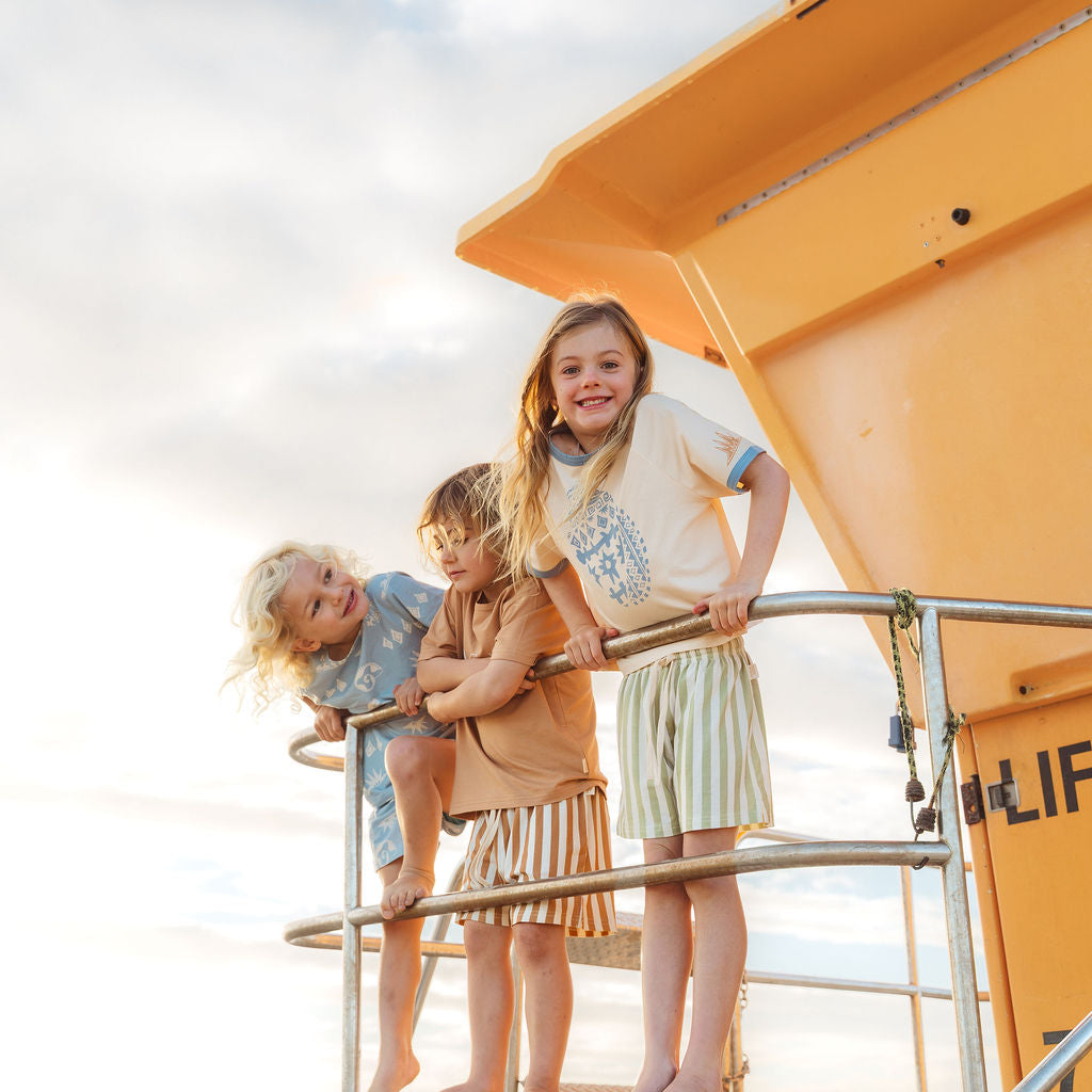 Three children standing at lifeguard station wearing Bam Loves Boo Spring 2026 collection 