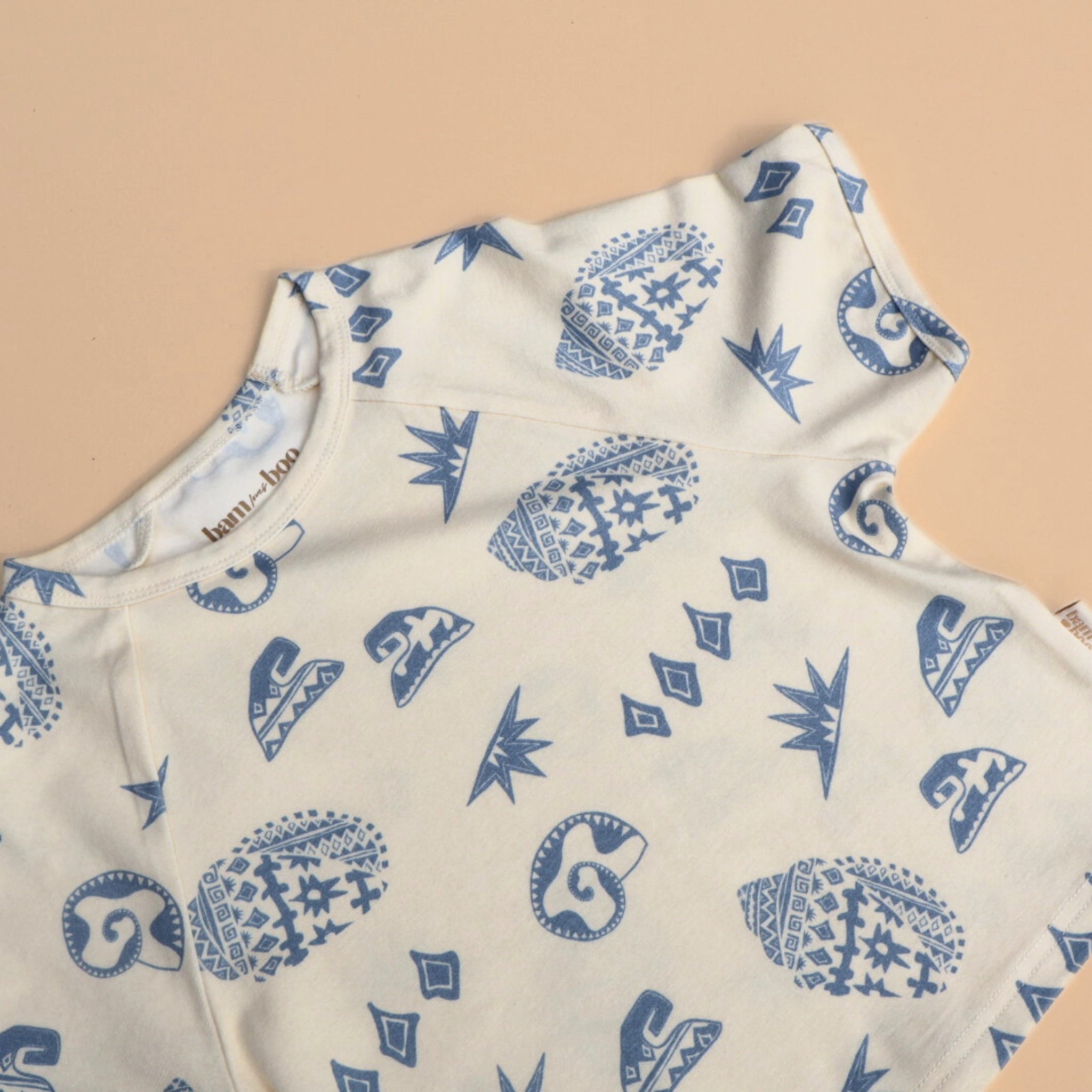 Kailani kids tee laid flat on a neutral backdrop, showing full beach-inspired shell and wave pattern.