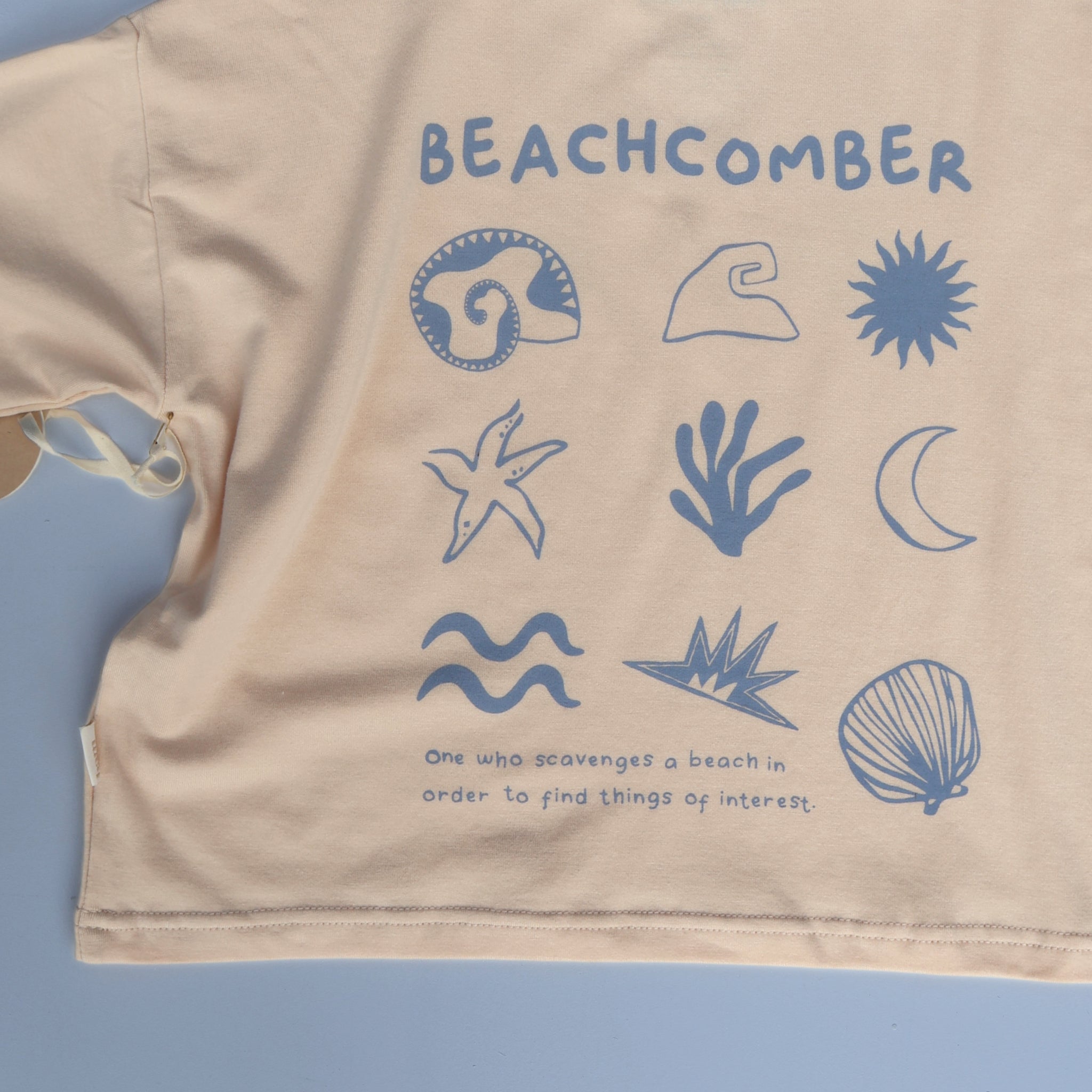Flat lay of Beachcomber long sleeve tee showing full  back prints in pale blue on cream base.