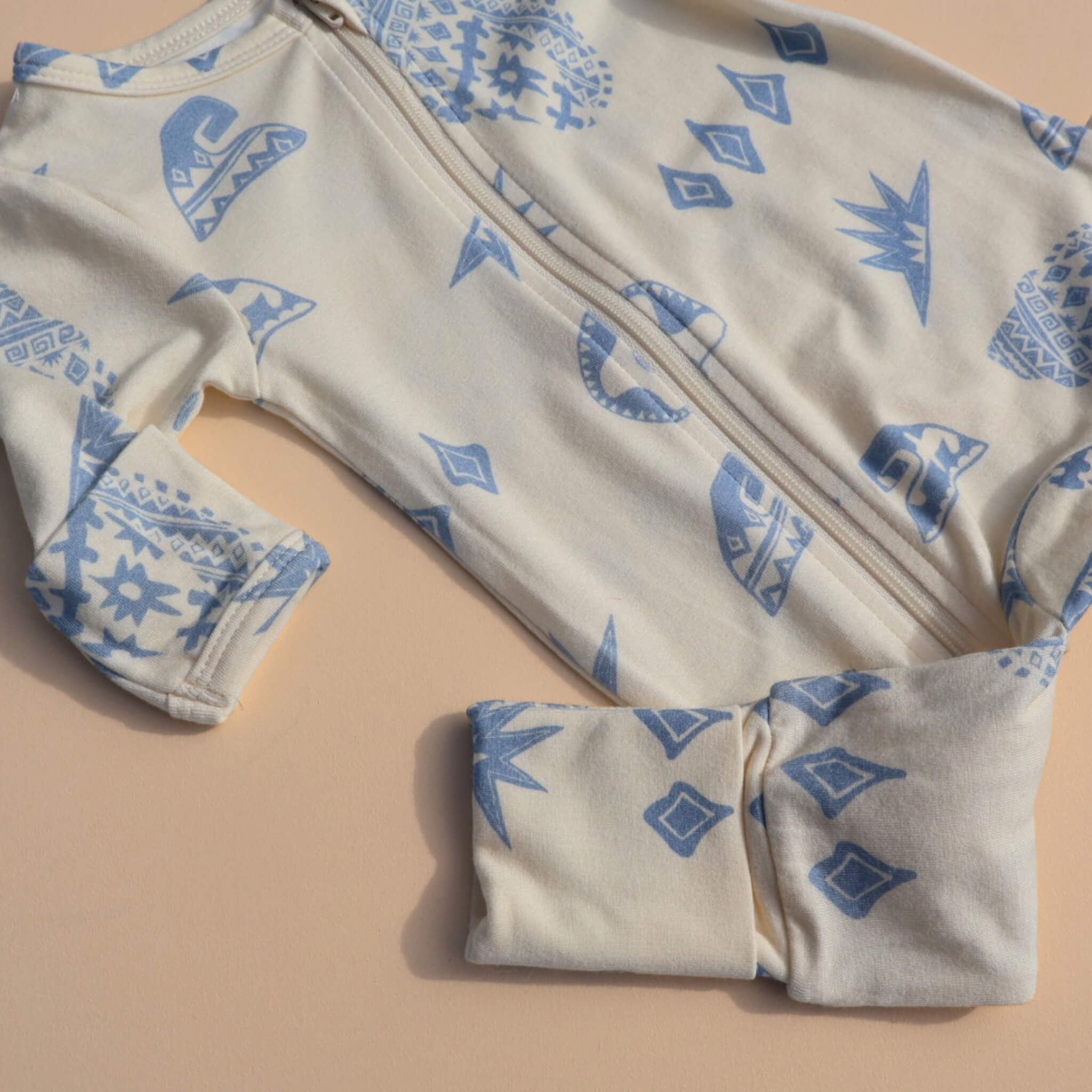 Baby onesie with blue geometric patterns on a beige background
