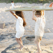 kids on beach carrying surf board wearing bam Loves Boo clothes