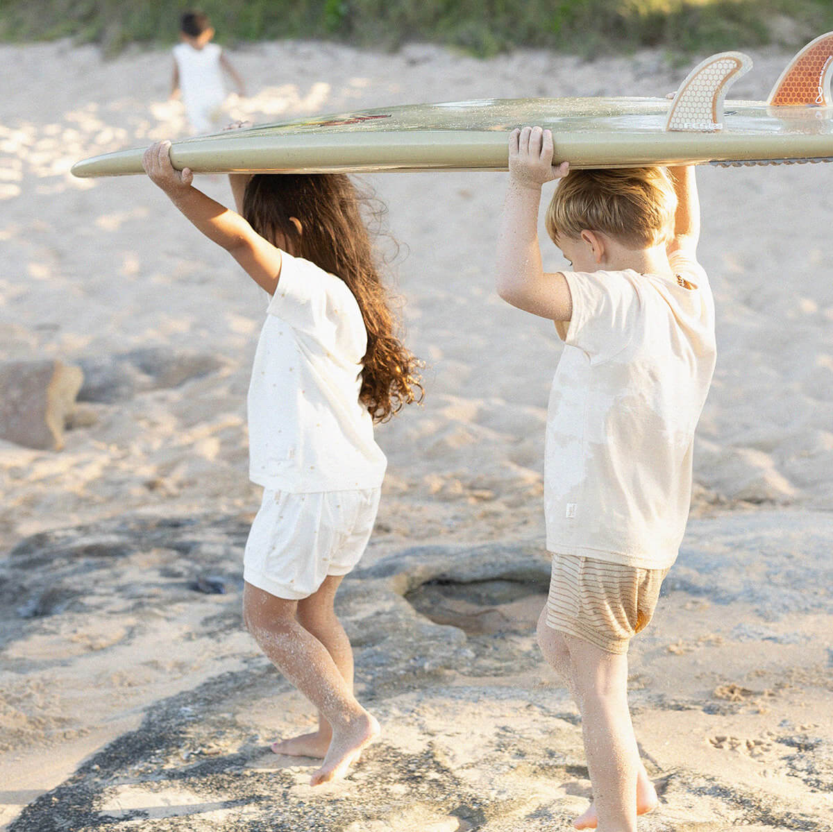 kids on beach carrying surf board wearing bam Loves Boo clothes
