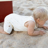 baby crawling on beach in cream playsuit with palm tree print