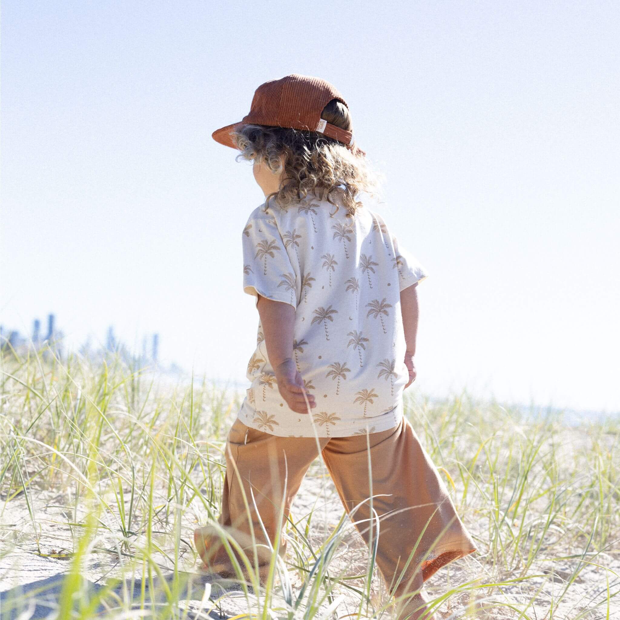 child on bear wearing cap palm tee and pants by Bam Loves Boo