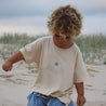 Child on beach in Tee make waves cream tee bamboo