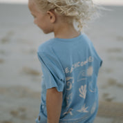 Child wearing a blue t-shirt with back print graphics beach design