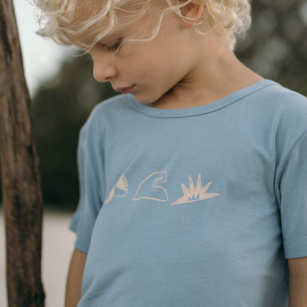 Child wearing a light blue t-shirt with a Shell wave sun logo 