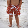 Boy on Australian beach wearing red boardshorts