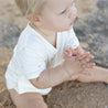 Baby wearing cream baby onesie with palm tree print