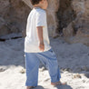 Child on beach in Blue pants and cream tee