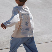 Child wearing a long-sleeve shirt with beach-themed graphics at skatepark