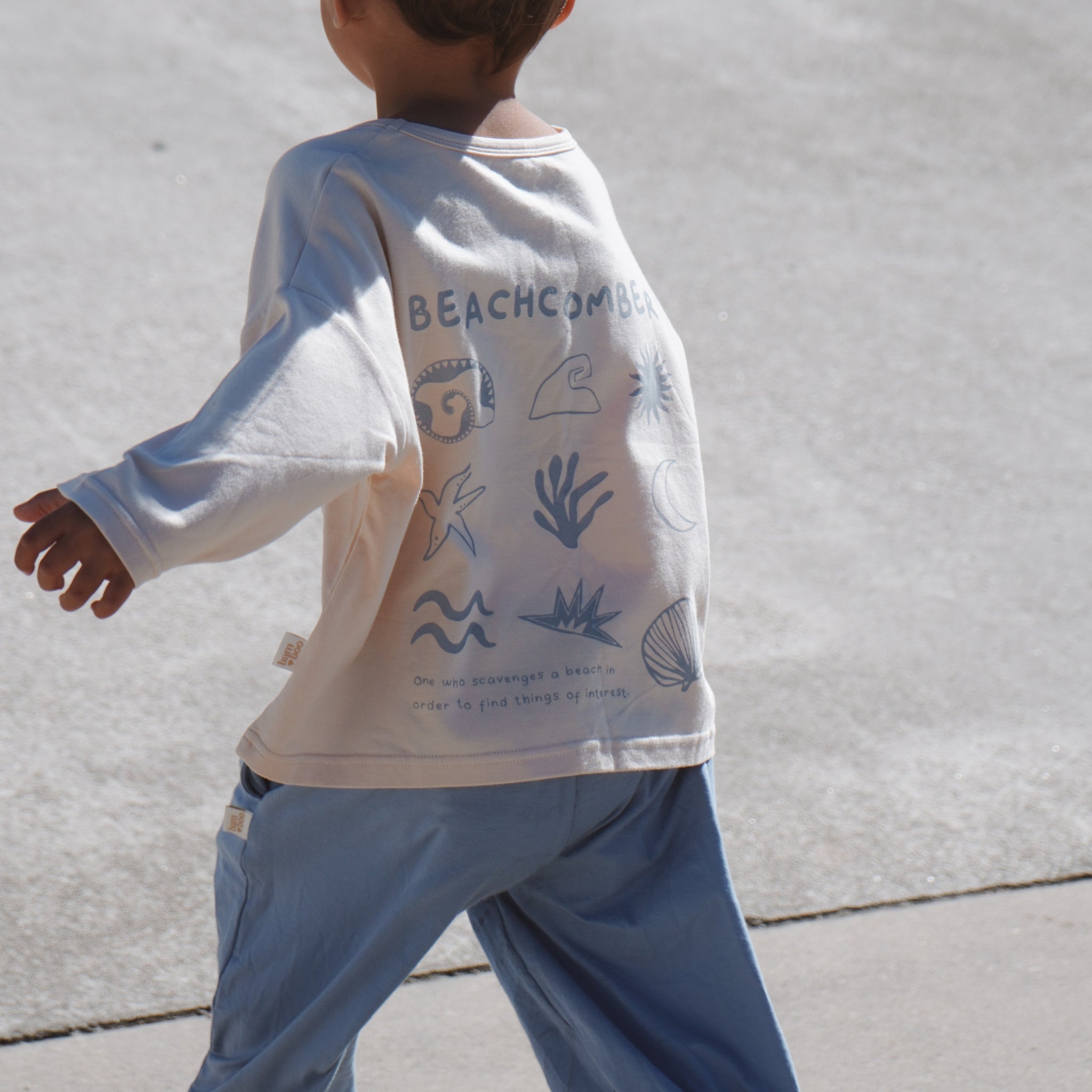 Child wearing a long-sleeve shirt with beach-themed graphics at skatepark
