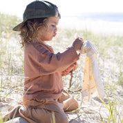 kid on beach wearing cap and bamboo clothes