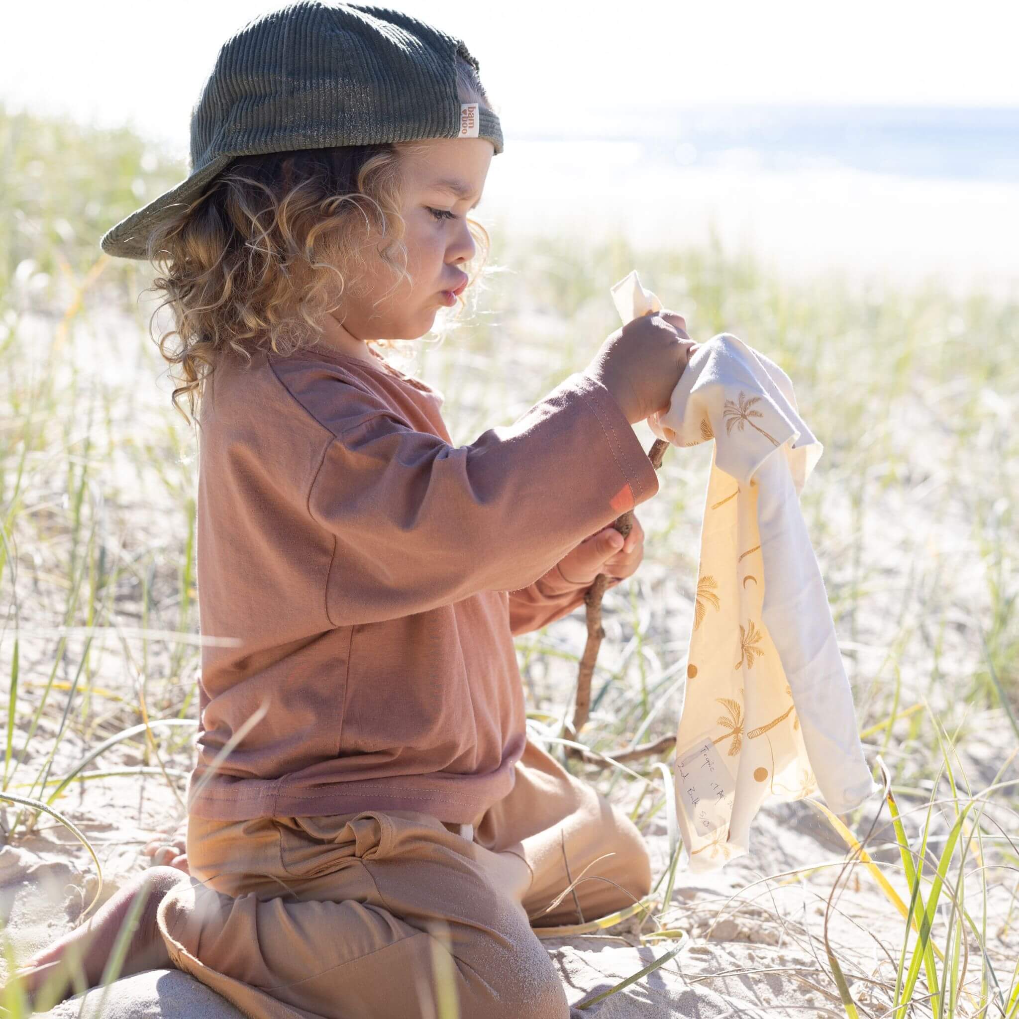 kid on beach wearing cap and bamboo clothes