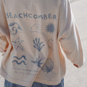 Back view of child wearing the Beachcomber long sleeve tee in bamboo organic cotton, featuring ocean-inspired illustrations in soft blue.