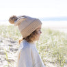 child on beach in winter pom pom beanie