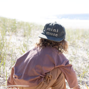 Green kids cap with mini muse embroidery on beach