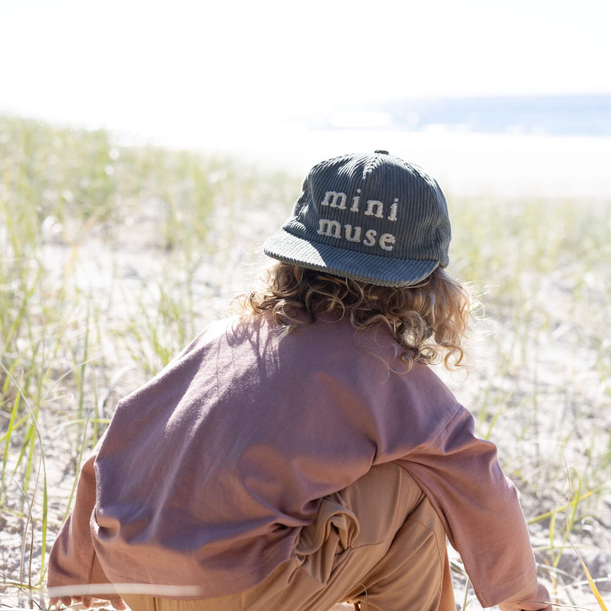 Green kids cap with mini muse embroidery on beach