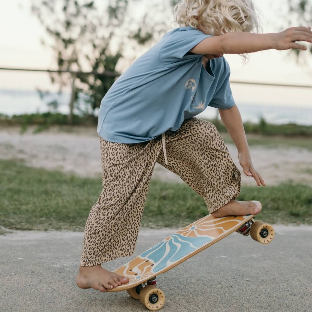 Child on a skateboard with leopard pants