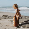 child carrying kids backpack on the beach