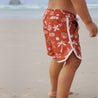 Boy wearing red boardies on beach