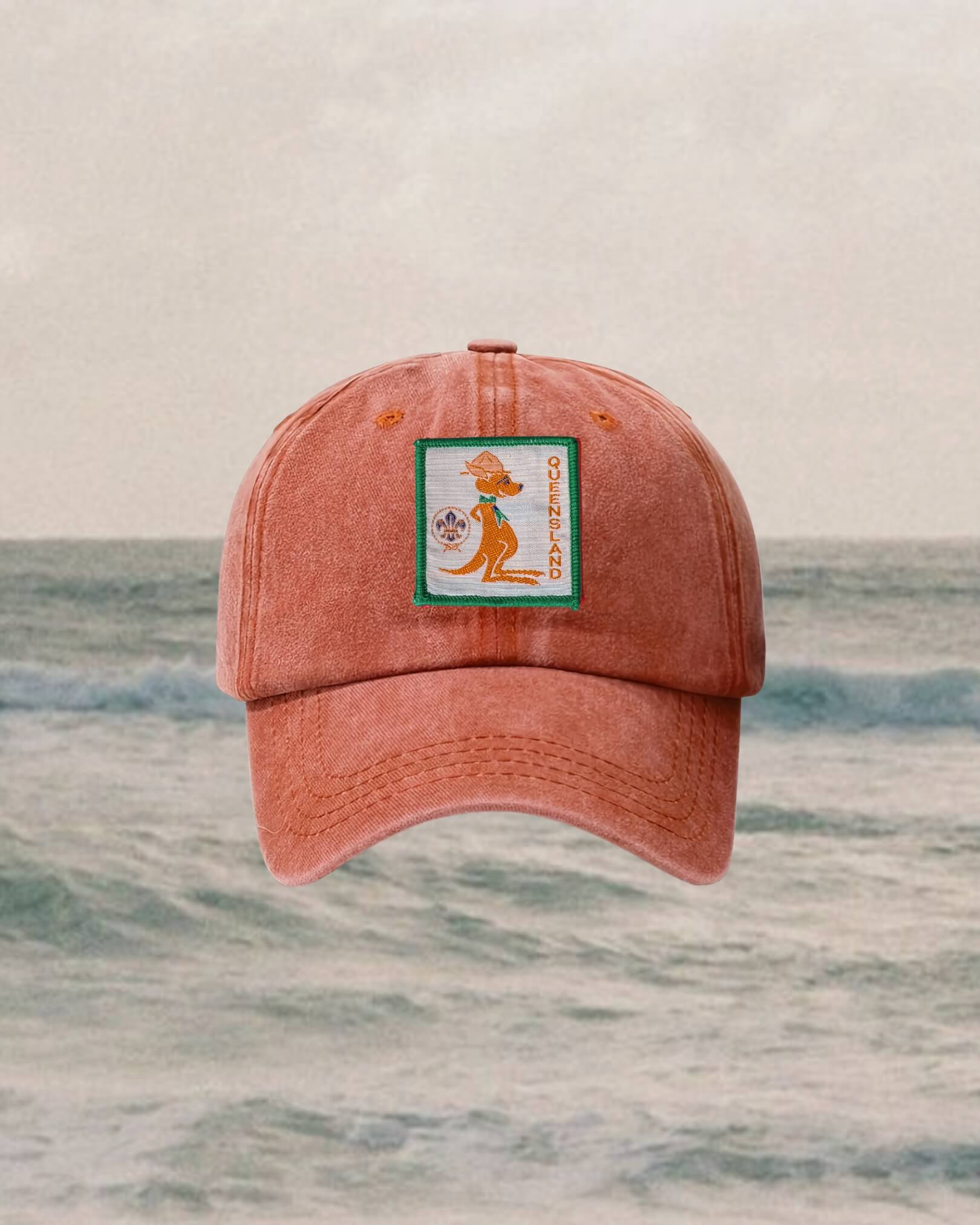 red kids cap with a badge on a background of ocean