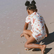 child wearing cream PJ's with Aussie summer print lobsters, prawns, shells, sun.