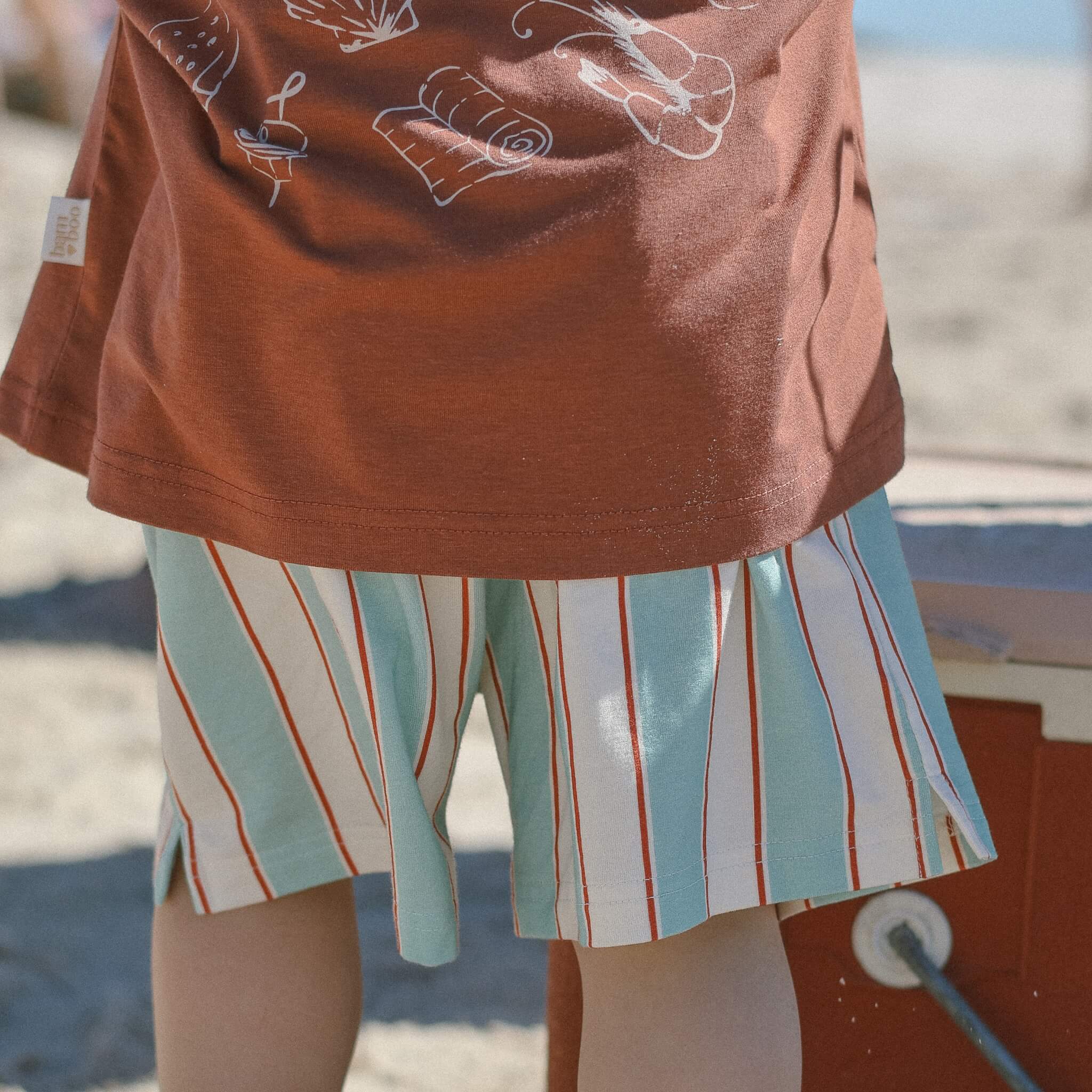 close up of child wearing shorts and tee on an beach