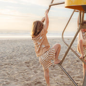 Child climbing a lifeguard tower in a tan Beachcomber print tee by Bam Loves Boo