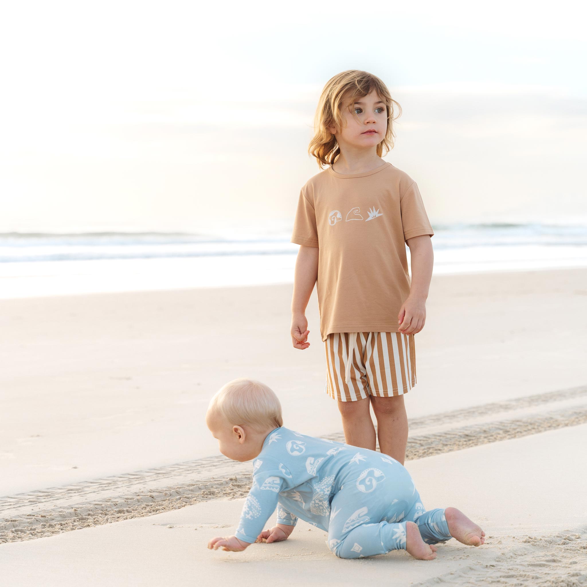 Child wearing a tan Beachcomber print tee on the beach by Bam Loves Boo