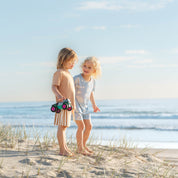 Kids chatting on the beach in tan and blue Kailani print pyjama sets by Bam Loves Boo
