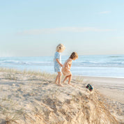 Child in a blue Kailani print bucket hat and pyjama tee drawing in the sand by Bam Loves Boo