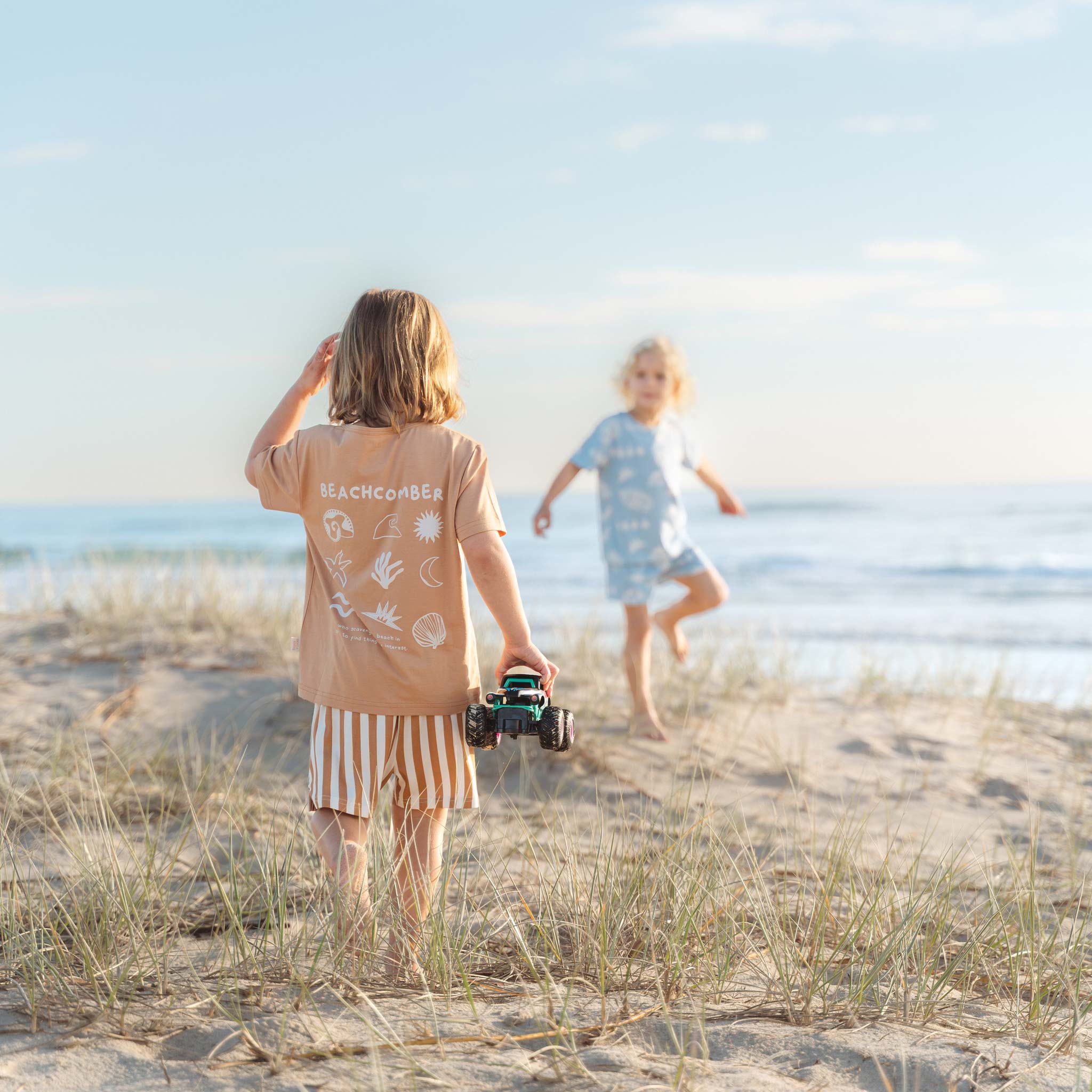 Child climbing a lifeguard tower in a Beachcomber tee and tan striped shorts by Bam Loves Boo