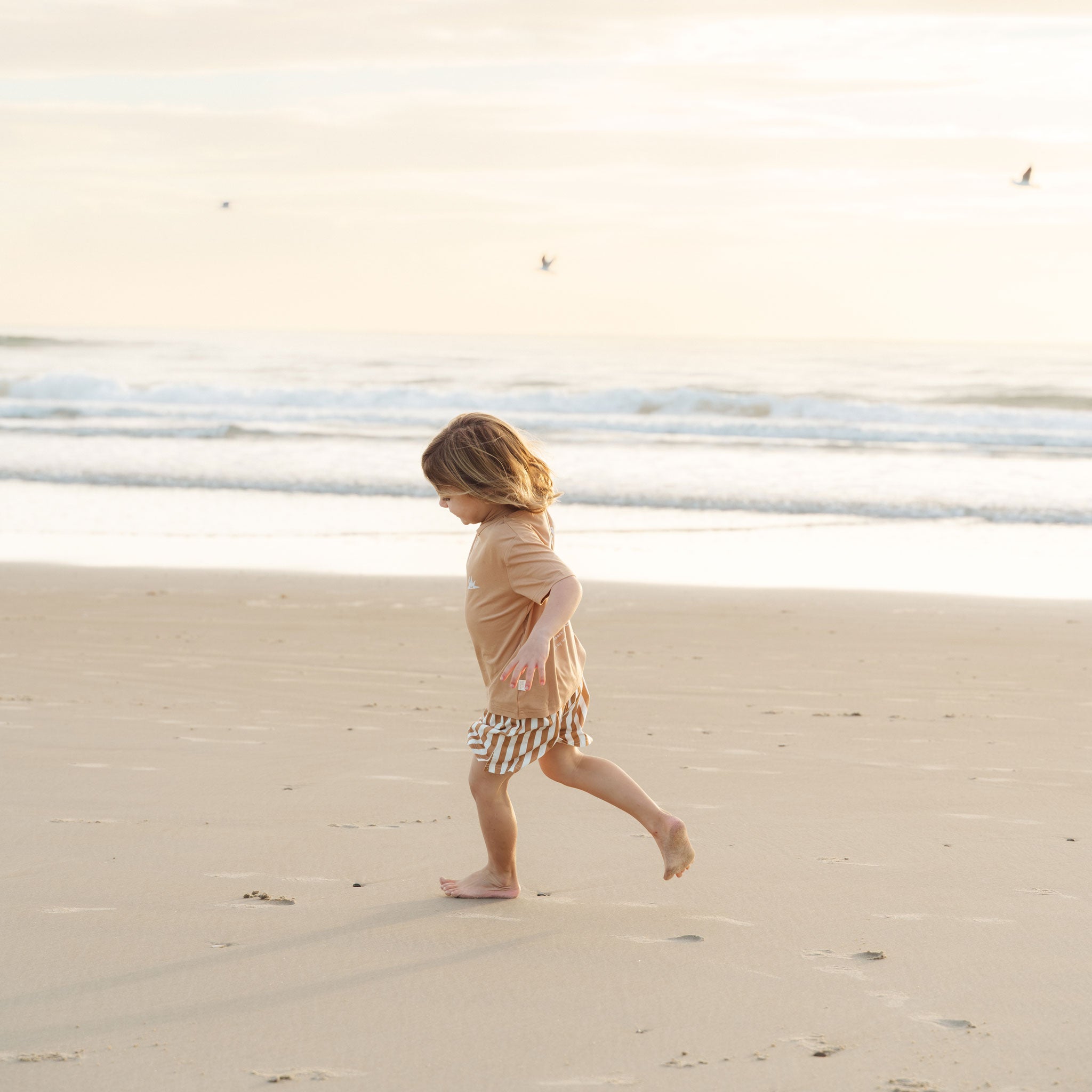 Kids playing on the sand dunes in tan and cream striped shorts by Bam Loves Boo