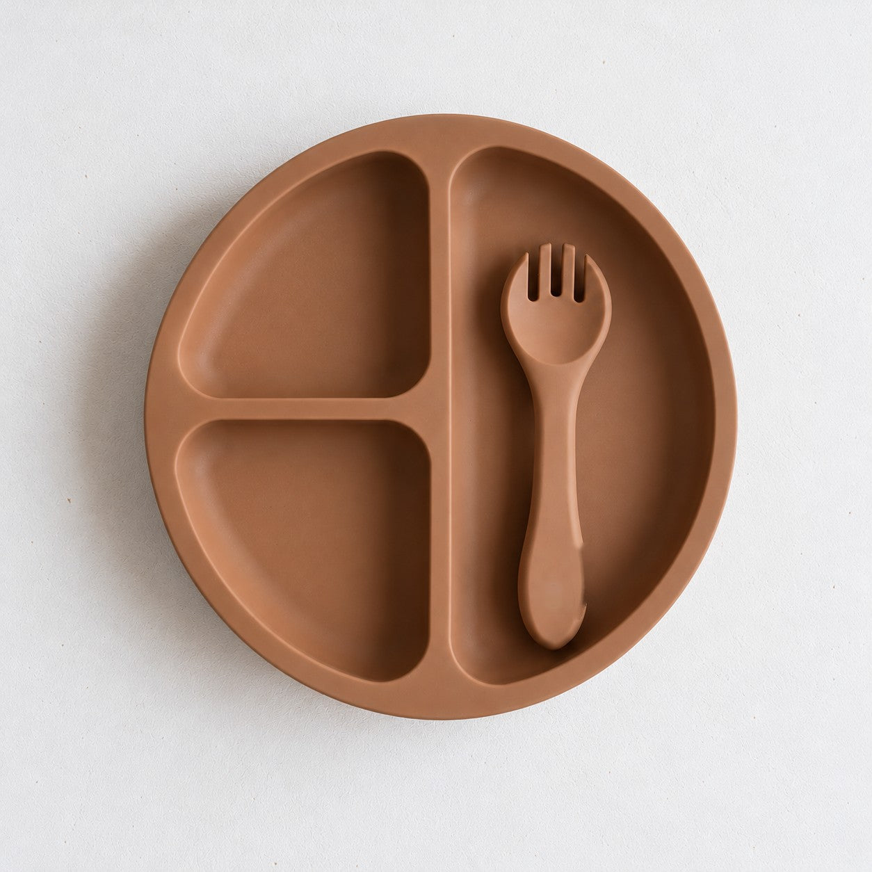 Clay silicone bento plate with three sections and matching fork, on a soft stone background