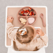 Baby eating from the Peach silicone bento plate in a high chair