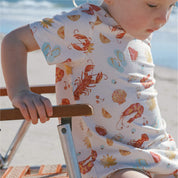 child wearing cream Tee with Aussie Christmas print lobsters, prawns, shells, sun printed 
