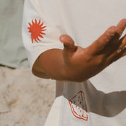 Close up of childs arm and sleeve with cream tee and red sun and watermelon printed on hem