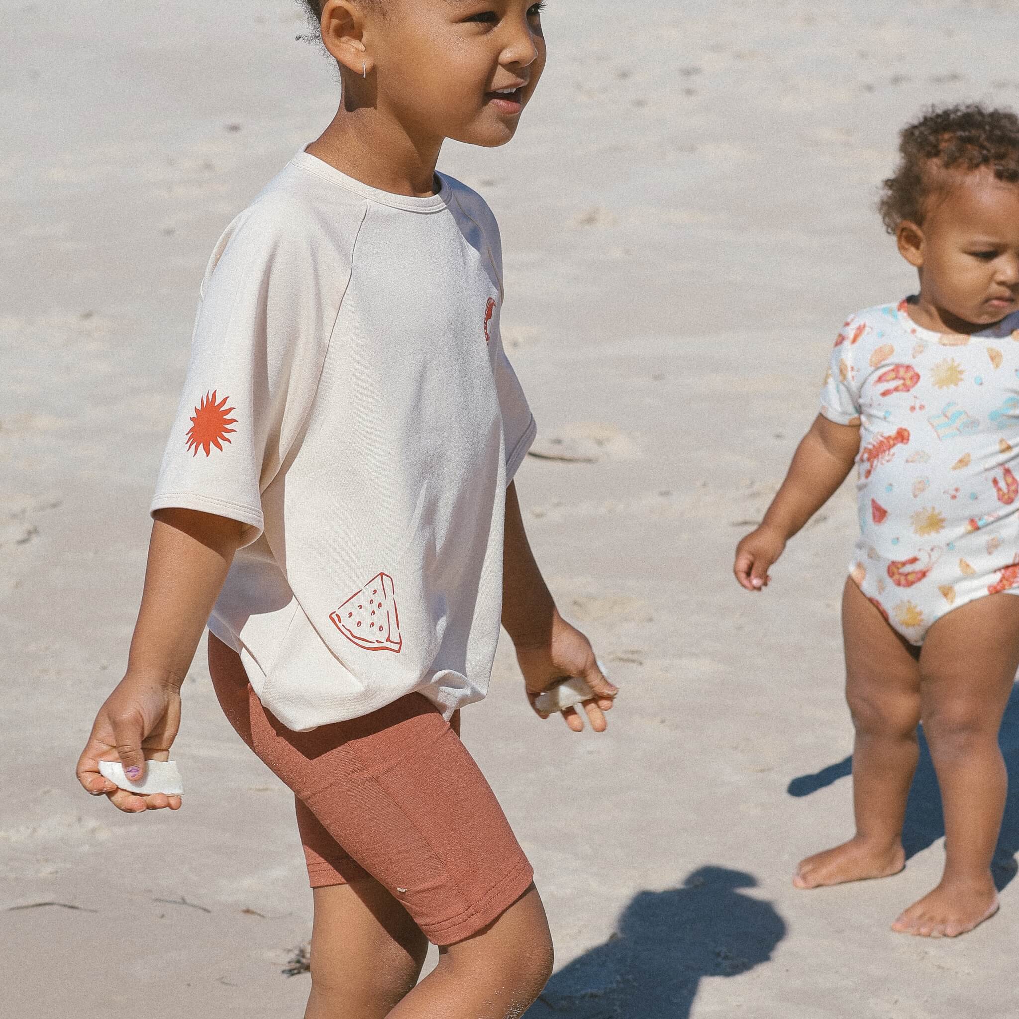 child-wearing-rust-bike-pants-cream-tee-on-the-beach