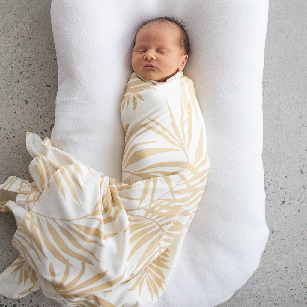 newborn baby swaddled in Hula palm bamboo jersey swaddle