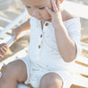 Baby wearing cream jumpsuit with palm tree print