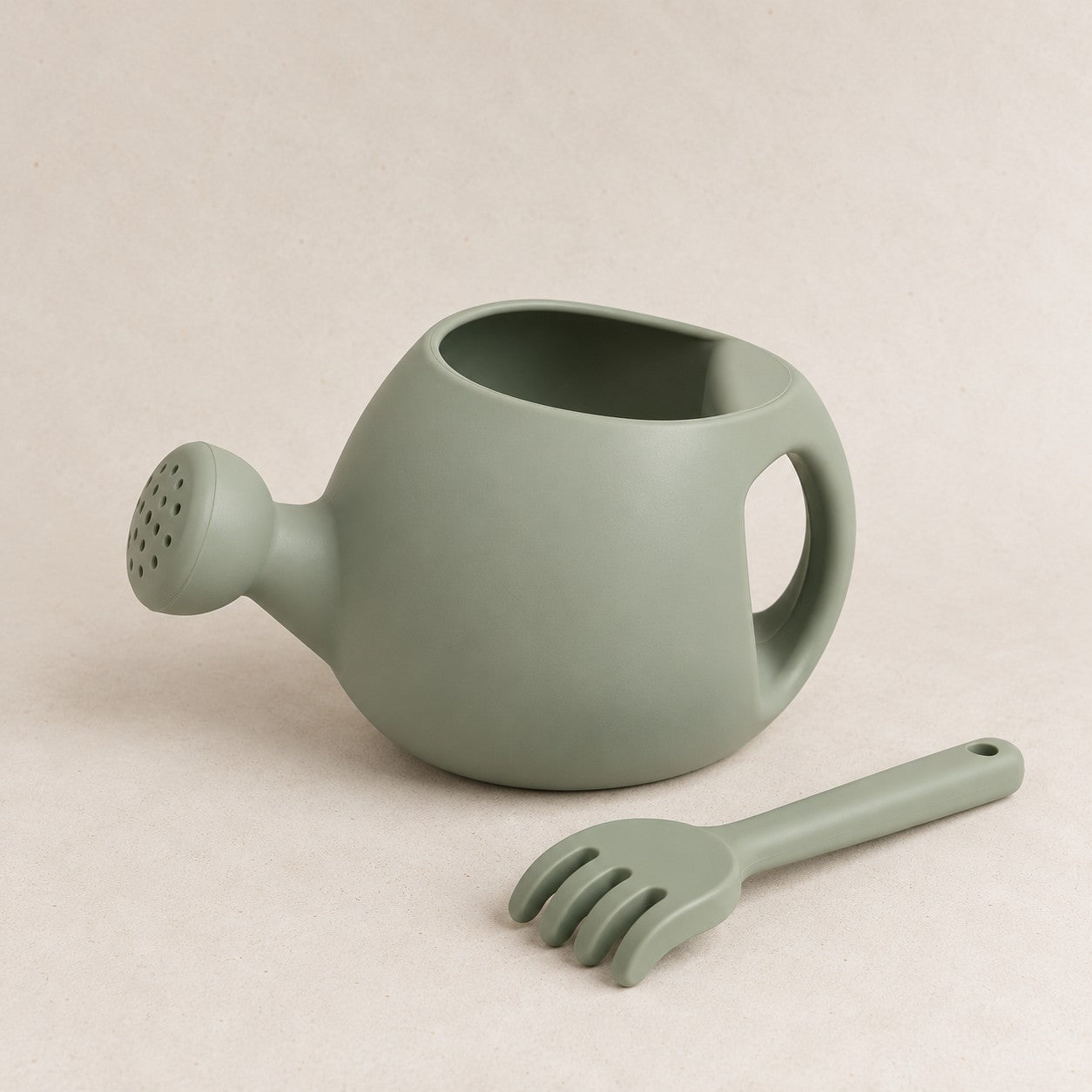 Sage silicone kids watering can and rake set, on a soft stone background