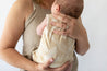 mother holding newborn baby wearing Palm leave beige and cream baby playsuit.By  Bam Loves Boo